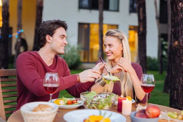 Alegre homem positivo compartilhando a salada com sua namorada — Fotografia de Stock