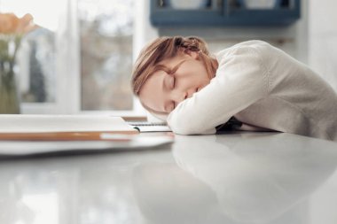 Küçük kız evde masanın üzerinde yatan bitkin