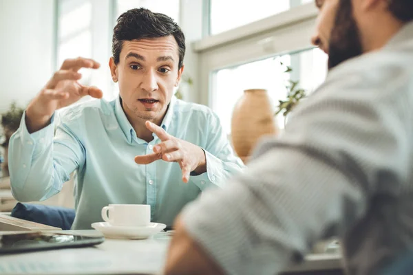 Inteligente joven agradable gesticulando en la cafetería — Foto de Stock