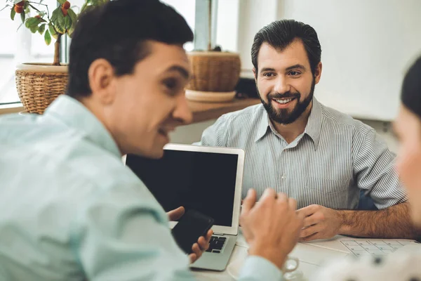 Joyful nice man sitting in front of the laptop