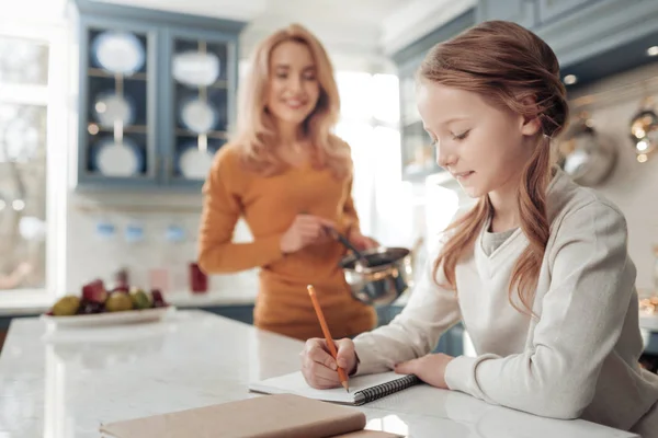 Ragazzina attenta prendere appunti in copybook — Foto Stock