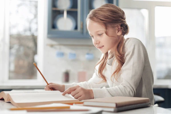 Attentive little schoolgirl reading her book at home — Stock Photo, Image