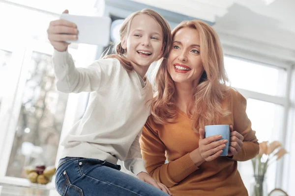 Привлекательные мать и дочь делают фотографии дома — стоковое фото