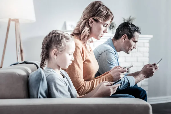 Padres concentrados y un niño usando sus teléfonos — Foto de Stock