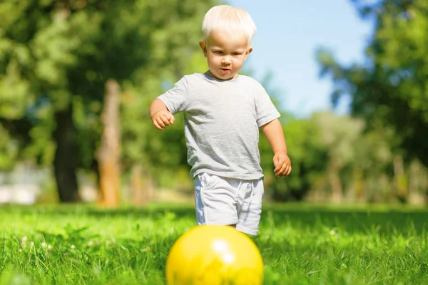 Niño concentrado jugando con la pelota afuera — Foto de Stock