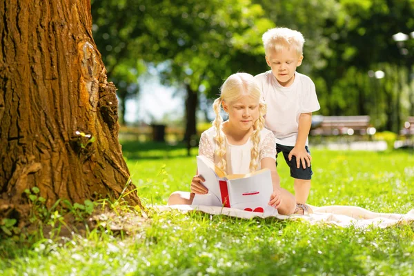 Atentos hermano y hermana leyendo un libro juntos — Foto de Stock