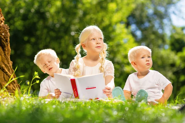 Dulces niños leyendo un interesante libro en el parque — Foto de Stock