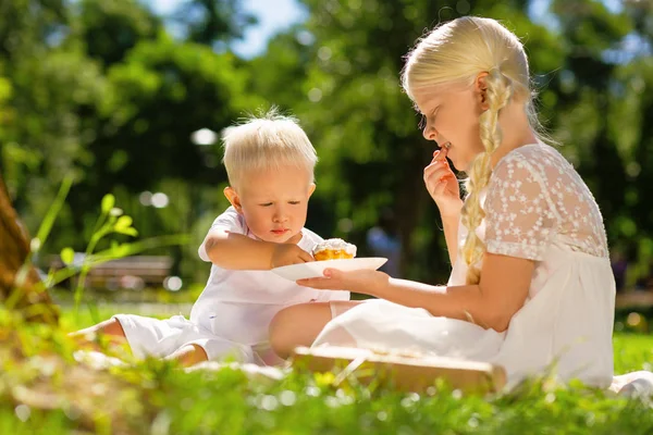Chica alegre y niño comiendo dulces en el parque —  Fotos de Stock