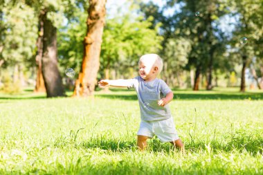 Bahçedeki sabun köpüğü ile oynayan mutlu çocuk