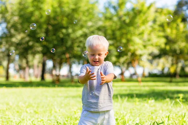 Niño atrapando hermosas burbujas de jabón afuera — Foto de Stock