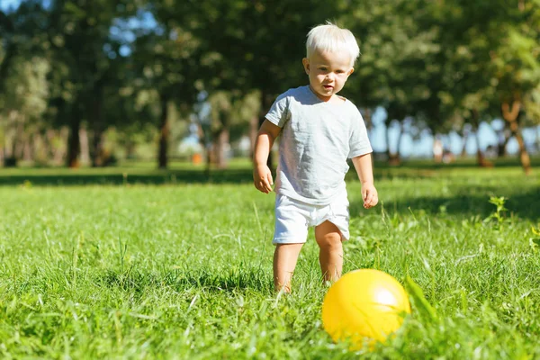 Lindo niño pequeño pateando una pelota afuera —  Fotos de Stock
