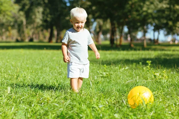 Sonriente chico pateando una pelota en el jardín — Foto de Stock