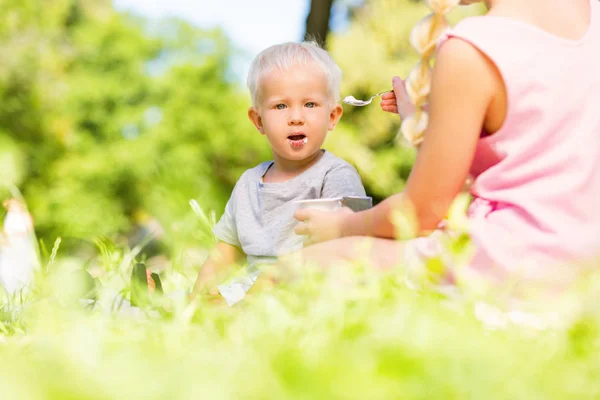 Temperamentní malé dítě jíst v parku — Stock fotografie