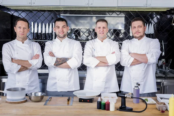 Great team of cooks standing in the middle of a kitchen