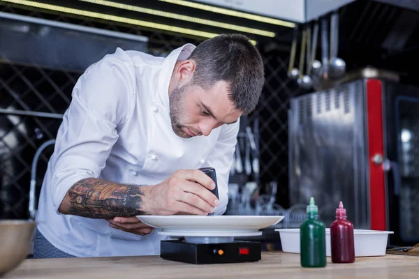 Cocinero joven concentrado preparando un plato secreto — Foto de Stock