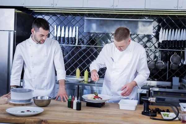 Jóvenes cocineros trabajando juntos en la cocina —  Fotos de Stock