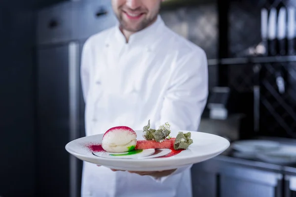Sonriente cocinero feliz sosteniendo un plato preparado —  Fotos de Stock