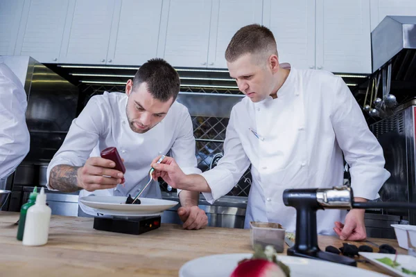 Jóvenes cocineros mezclando ingredientes en el plato —  Fotos de Stock