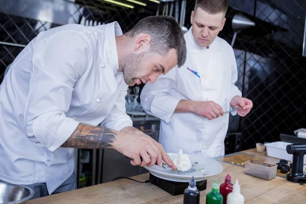 Guapos cocineros tratando con diferentes recetas nuevas —  Fotos de Stock