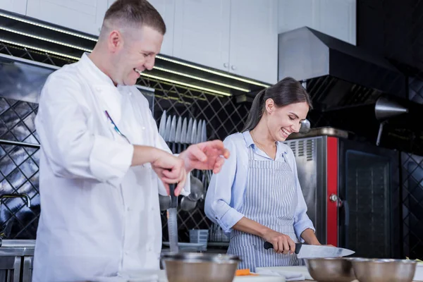 Cocinero experimentado mostrando nuevos métodos de cocinar a una dama —  Fotos de Stock