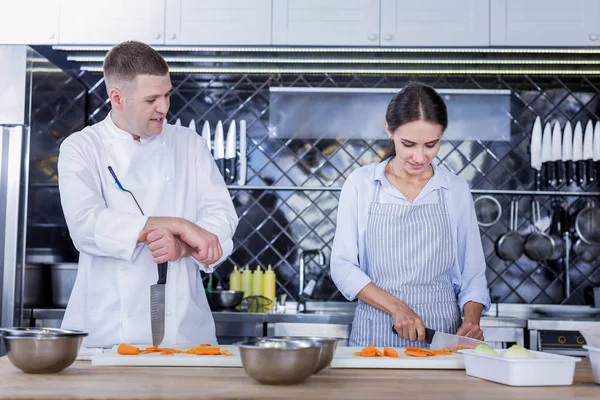 Jovencita cocinando un sabroso plato con un chef — Foto de Stock