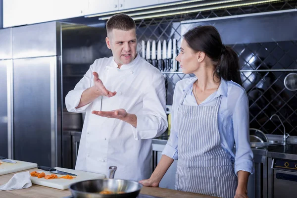 Cocinero serio dando diferentes consejos a un joven cocinero —  Fotos de Stock