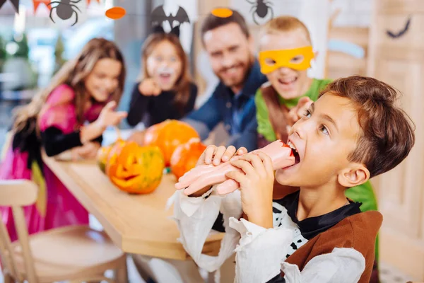 Emocionado chico emocional con disfraz de Halloween tratando de galletas de mano — Foto de Stock