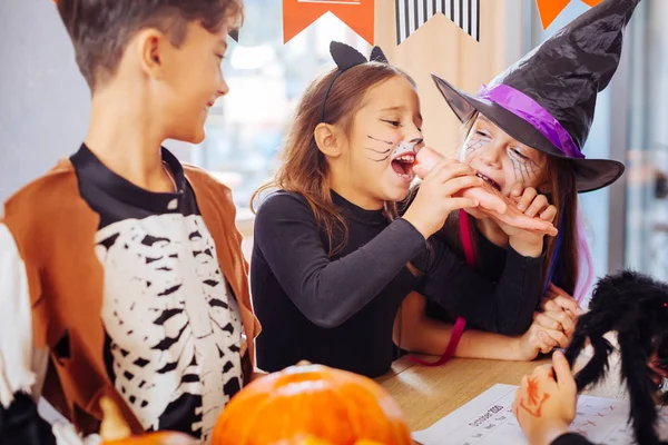 Two girls wearing Halloween costumes trying sweet hand Halloween cookie — Stock Photo, Image