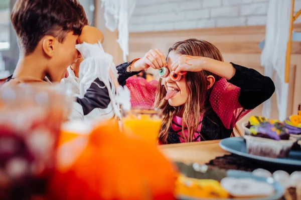 Kinderen elkaar schrikken terwijl het hebben van cookies in de vorm van de ogen voor Halloween — Stockfoto