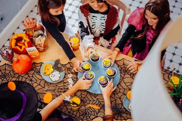 Niños con disfraces sentados a la mesa y comiendo dulces de Halloween —  Fotos de Stock