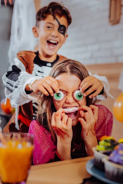 Brother and children feeling funny while eating thematic sweets for Halloween — Stock Photo, Image