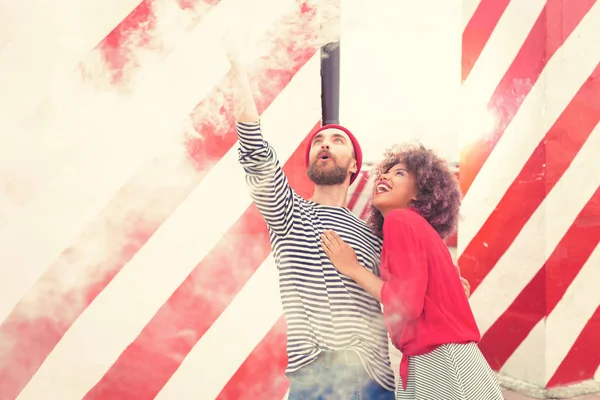 Emotional woman laughing while her boyfriend holding smoke flare