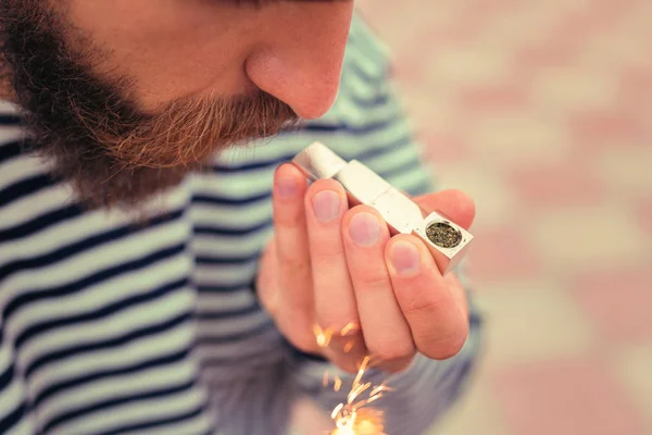 Bearded young man using the lighter for lighting his pipe — Stock Photo, Image