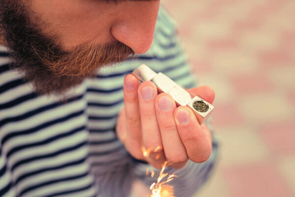 Bearded young man using the lighter for lighting his pipe