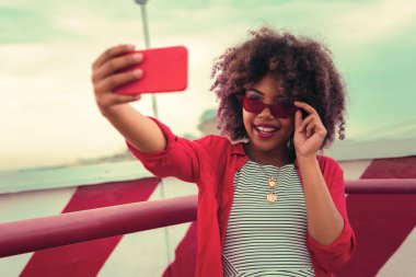 Kırmızı gözlük takan ve harika selfies alarak çekici genç kadın