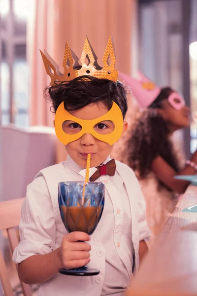 Little boy drinking juice with sipping straw while being at masquerade — Stock Photo, Image