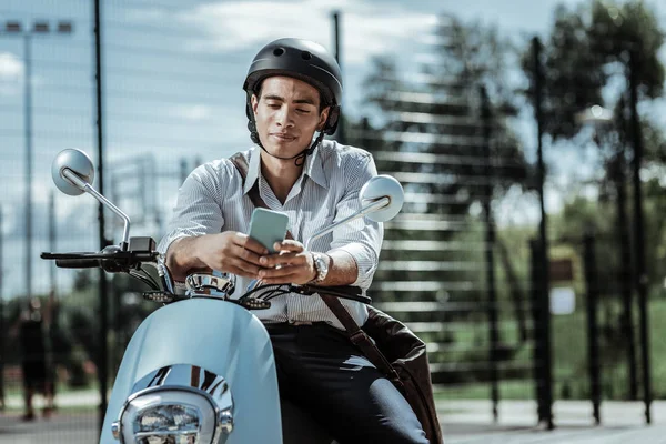 Estudiante masculino pensativo chequeando horario en moto — Foto de Stock