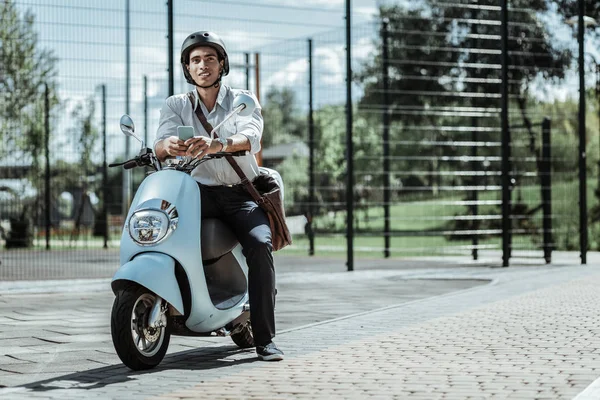 Reflective male student typing friends on motorbike — Stock Photo, Image