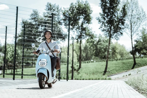 Merry male student riding to university on motorbike — Stock Photo, Image