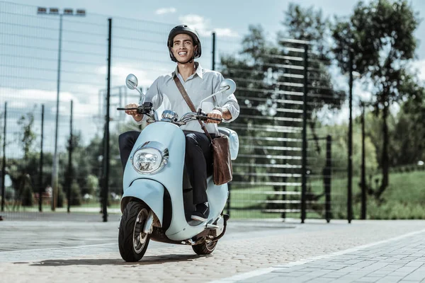 Optimistische männliche Studenten, die mit dem Motorrad zur Universität fahren — Stockfoto