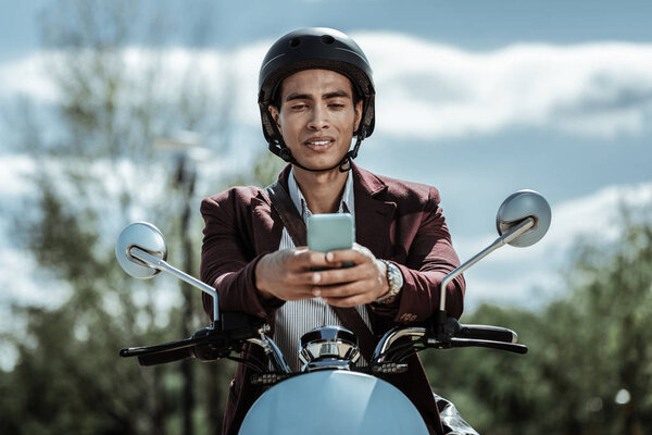 Serious pleasant guy surfing Internet on motorbike