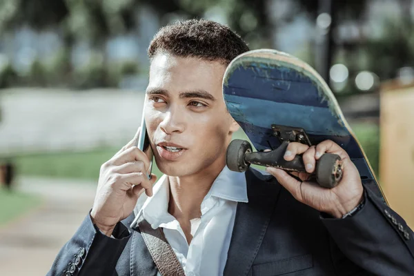 Charming male student calling friends with skateboard — Stock Photo, Image