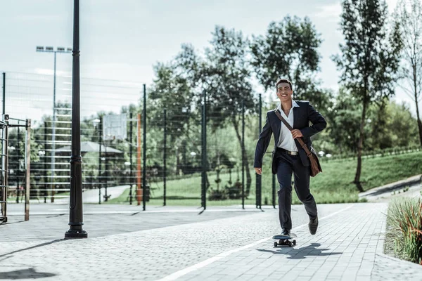 Schöner männlicher Schüler auf dem Rückweg vom Unterricht mit dem Skateboard — Stockfoto
