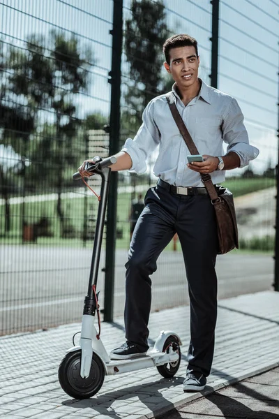 Pensativo chico dudoso activando su scooter eléctrico — Foto de Stock