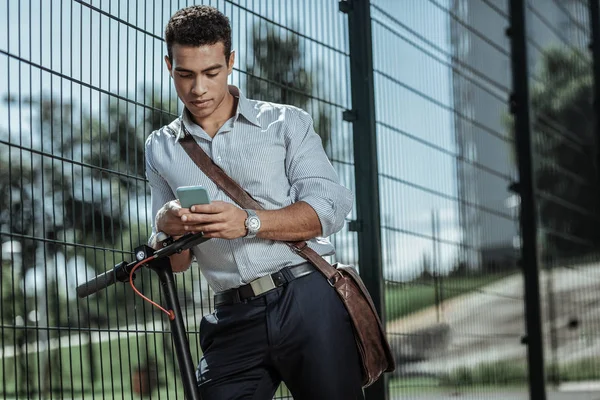 Ernsthafter angenehmer Kerl, der Meilen am Telefon überprüft — Stockfoto