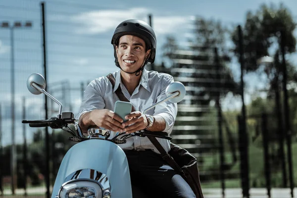 Sincere optimistic guy reconsidering answer on motorbike — Stock Photo, Image