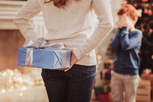 Dikkat et anne oğlu için bir hediye tutarak arkadan görünüş — Stok fotoğraf