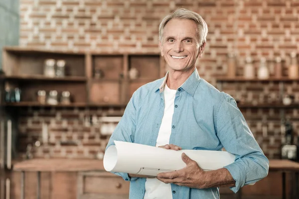 Vrolijke ervaren ingenieur een blauwdruk te houden — Stockfoto