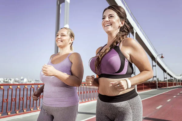 Positive donne gioiose che corrono insieme sul ponte — Foto Stock