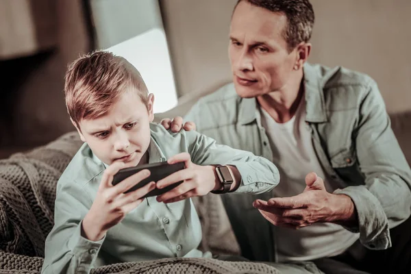 Irritated boy trying to play game on gadget